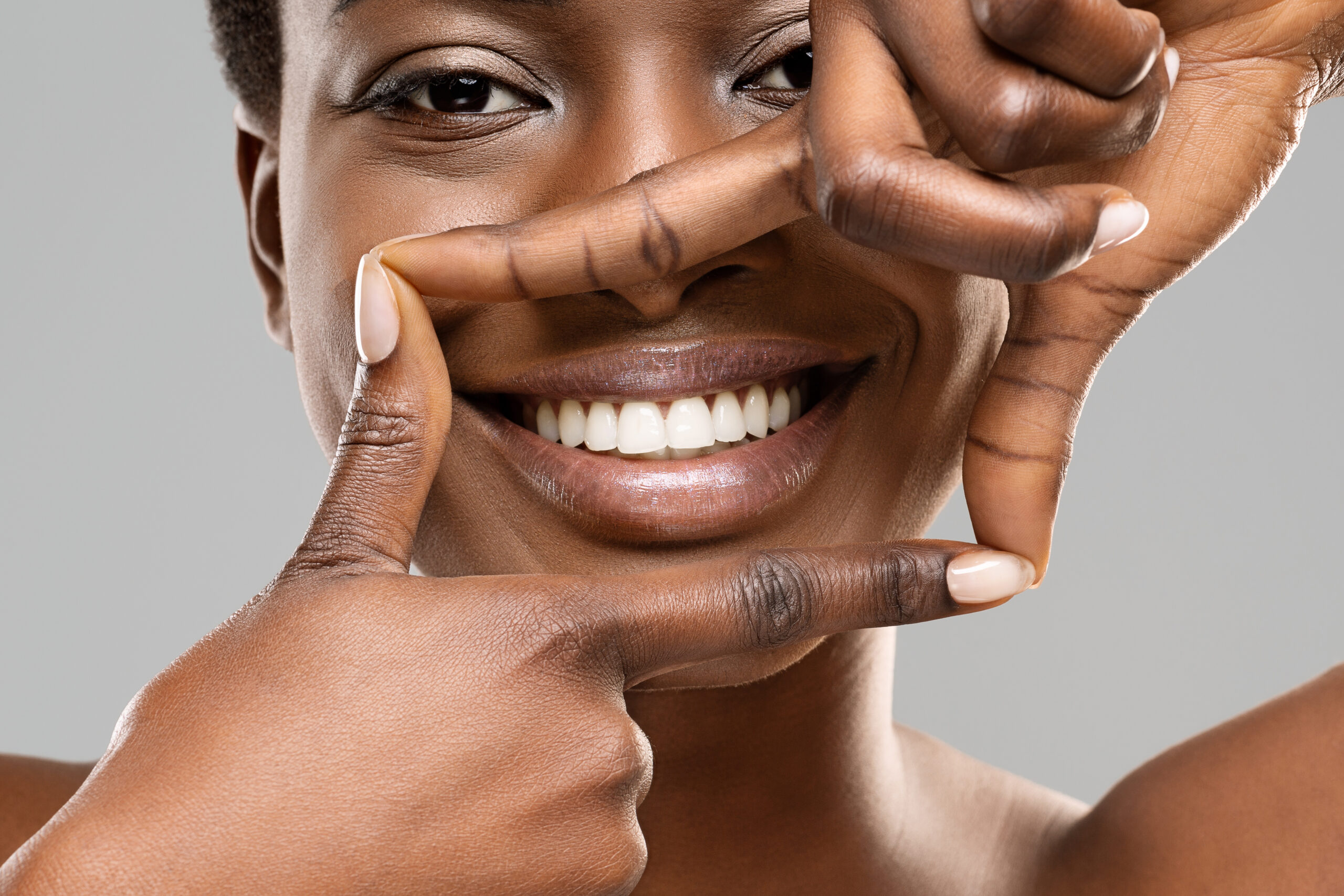 Woman with beautiful smile framing her teeth with her fingers